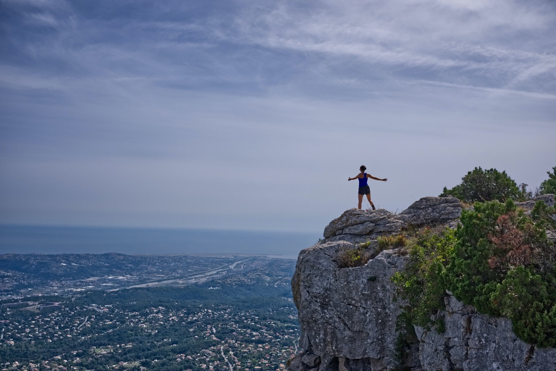 a woman standing on a mountain with outstretched arms to symbolise ambition
