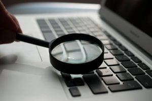 A magnifying glass over a keyboard. Representing the importance of searching for the right people to network with.