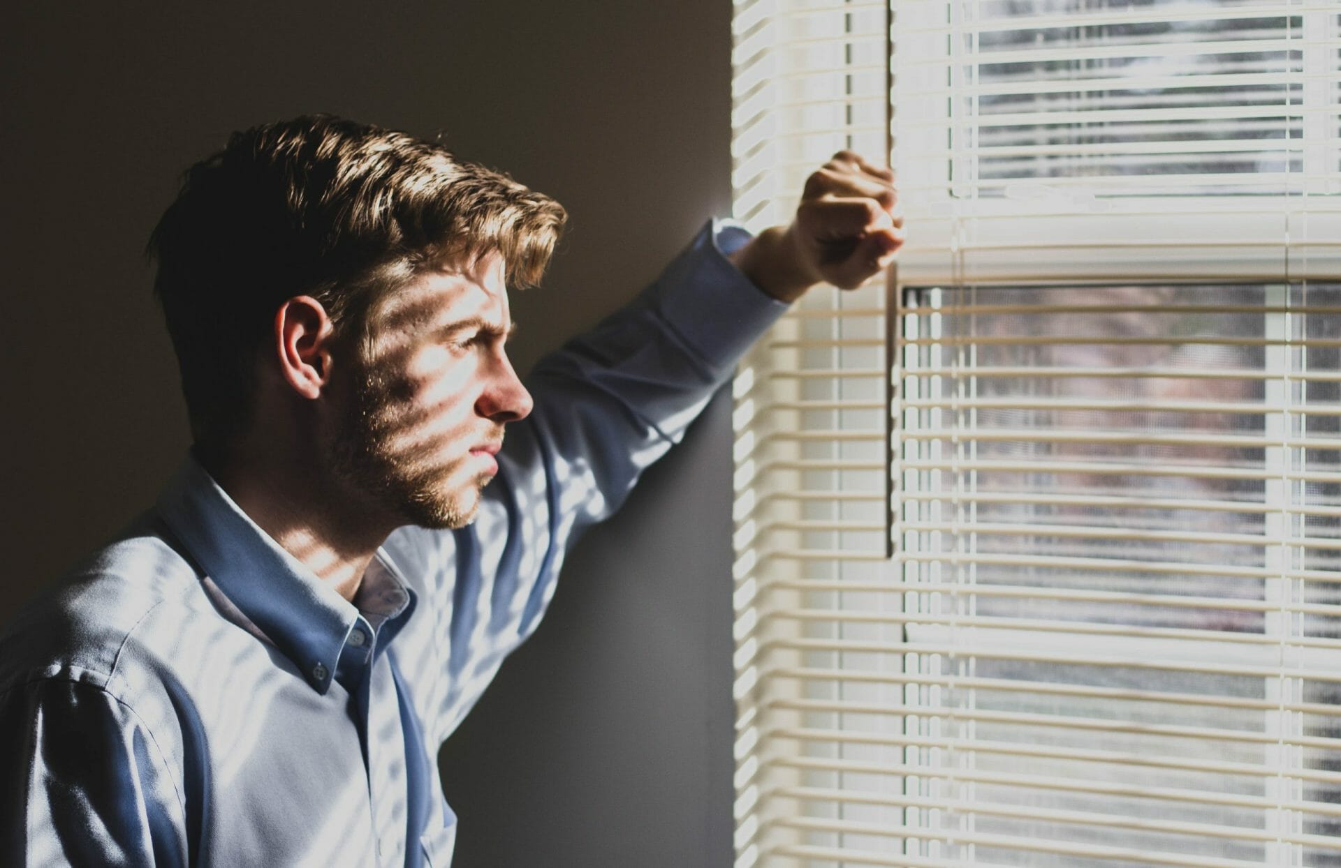 a man gazing out of the window looking sad to represent the cons of moving from industry to practice